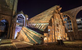 The wooden structure pictured at night and lit from within