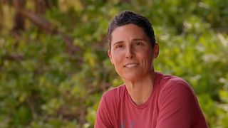 Kristin wears a red shirt and talks during a confessional in the woods on Survivor.