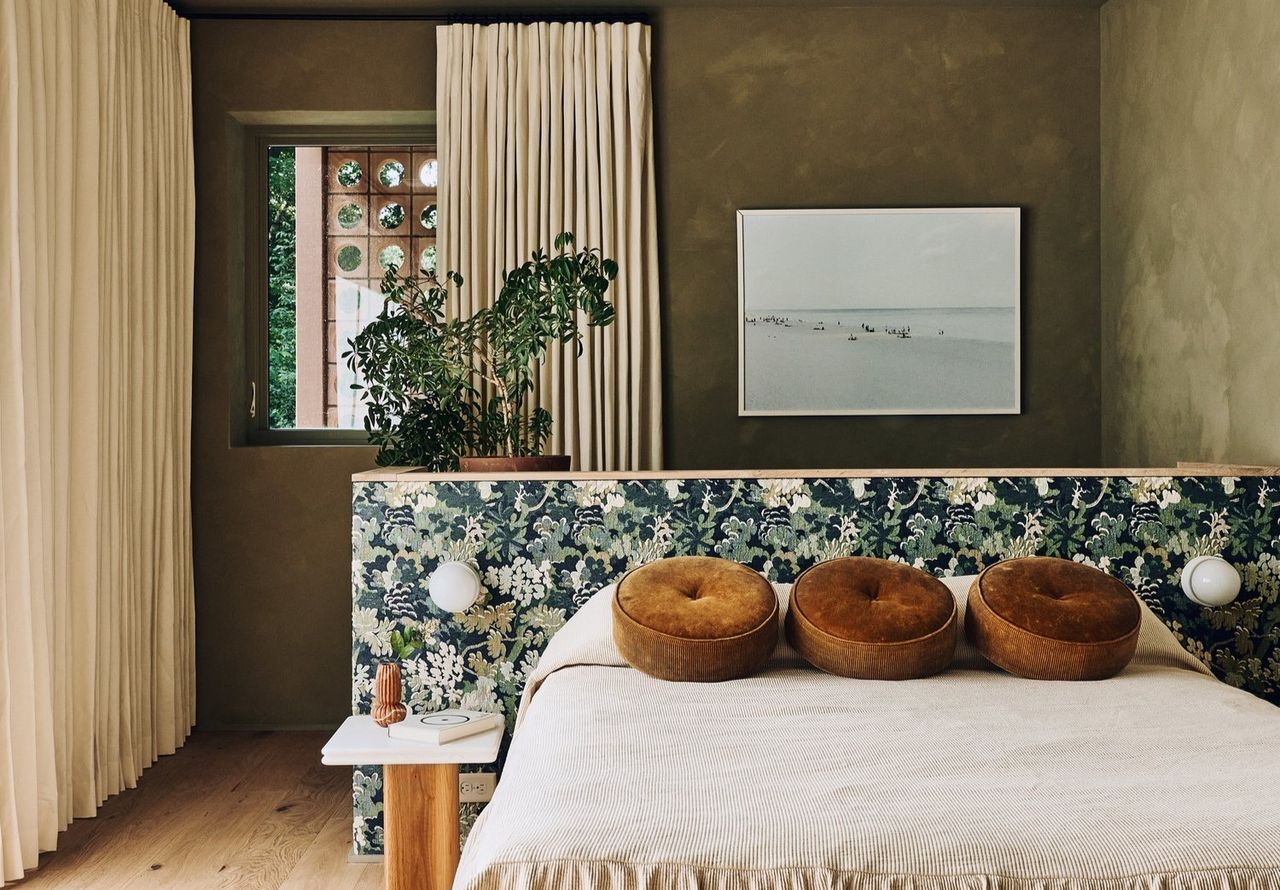 A bedroom with khaki walls and taupe pillows