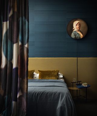 An example of dark bedrooms showing a bedroom with dark teal walls and a yellow ochre bedhead