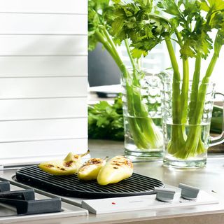 kitchen with white wall induction hob grill and glass with leafy vegetable
