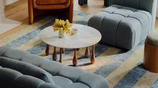 a blue sofa, striped rug and coffee table with irregularly shaped legs