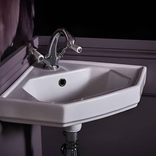 white corner sink in black bathroom 