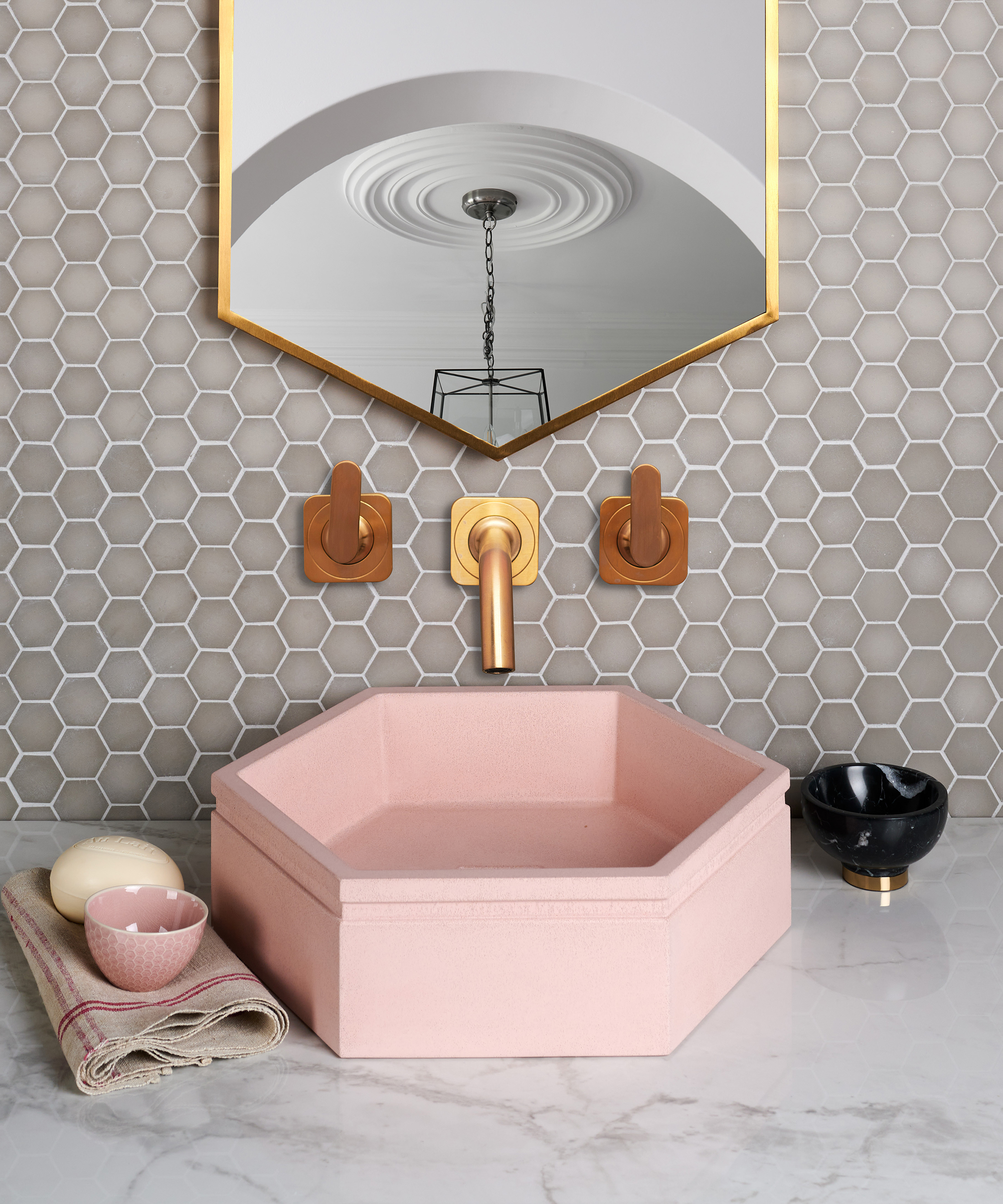 A hexagonal gray tiled Ca' Pietra bathroom with pink sink.