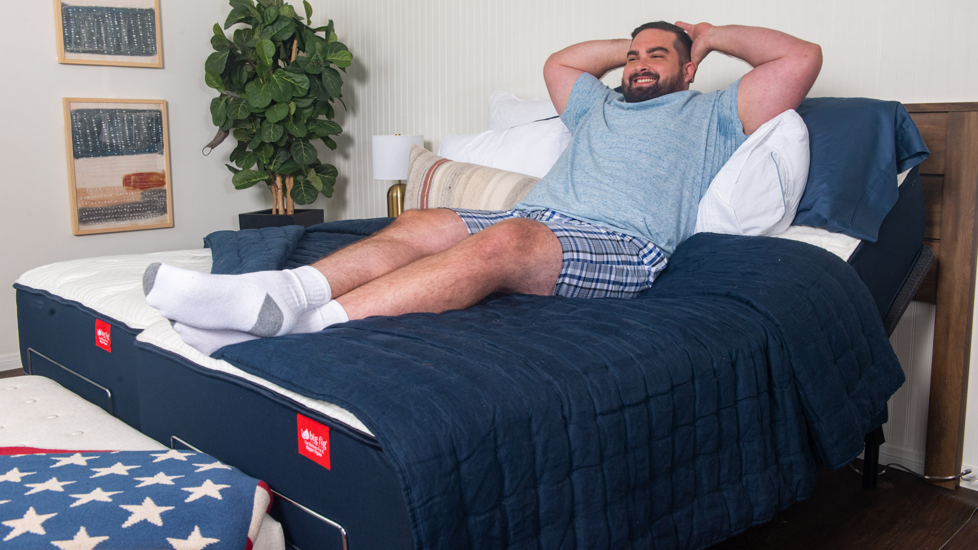 A man in a blue t-shirt relaxes on the Big Fig hybrid mattress