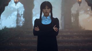 Wednesday standing with her arms crossed across her chest in Season 2 of Wednesday.