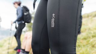 Close up of women's legs in leggings with hiker in the background