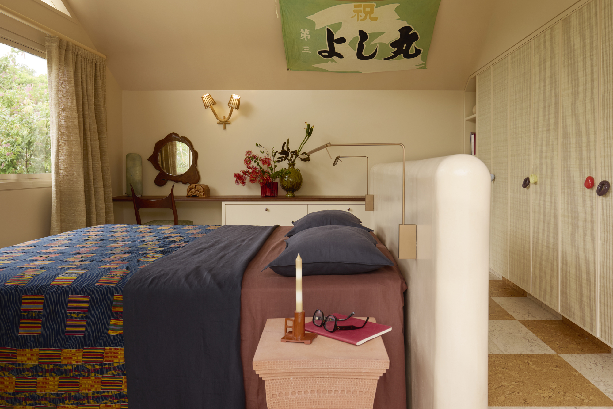 A bedroom with a bed in the middle of the room styled with pink and blue checkered bedding