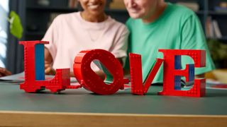 Lego Love sign in front of a pair of people smiling