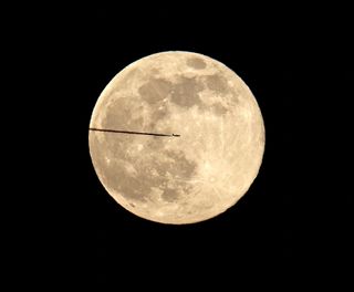 view of the moon with a plane flying across it