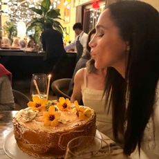 Meghan Markle sitting in a restaurant blowing out the candles on a cake 