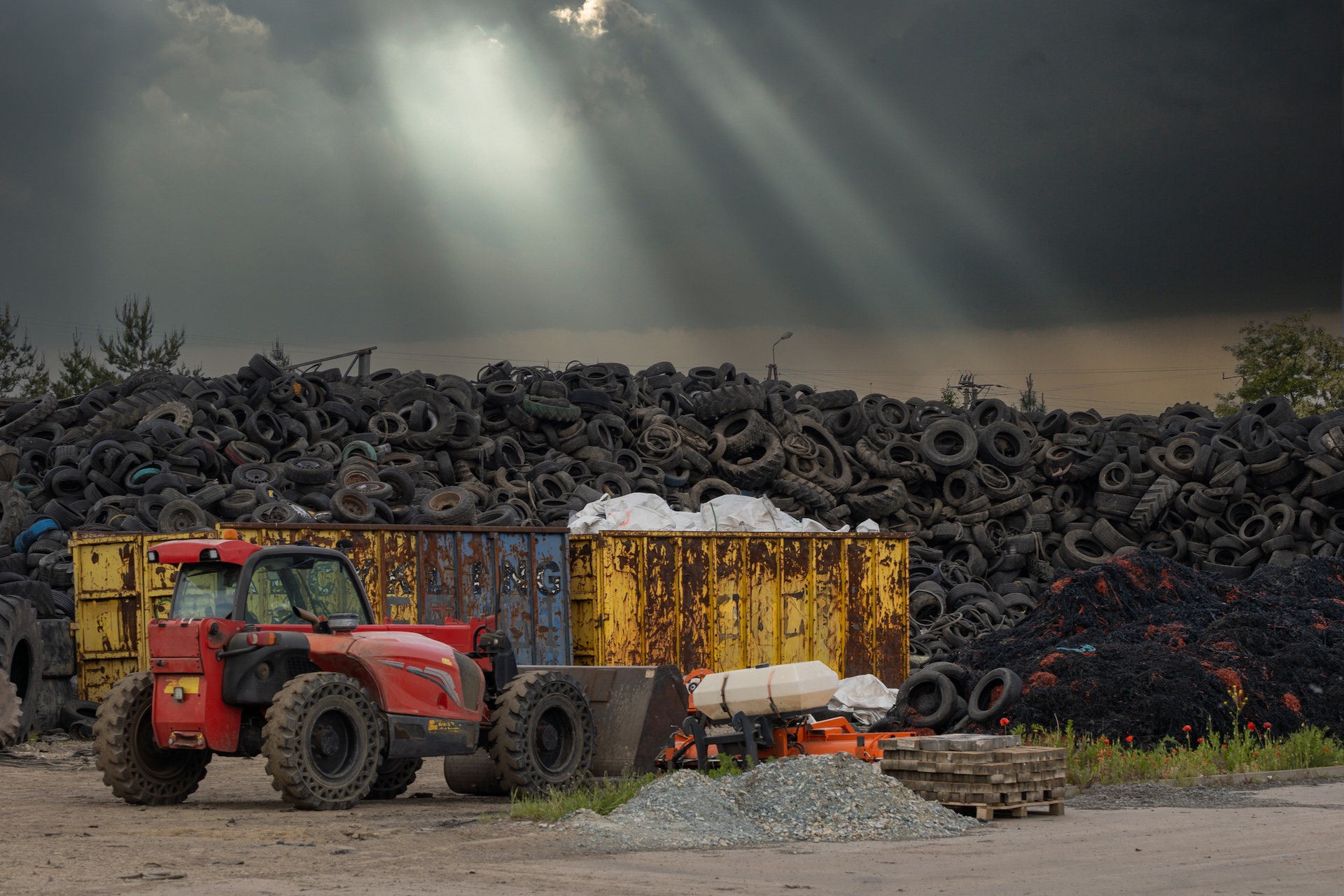 piles of used tires with forklift and dumpster in foreground