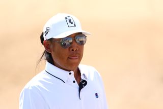 Anthony Kim wearing sunglasses and a white cap and polo