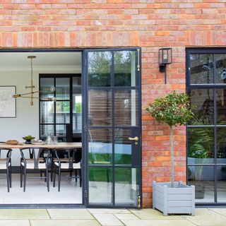 Exterior of red brick house with metal bifold doors and black metal wall light