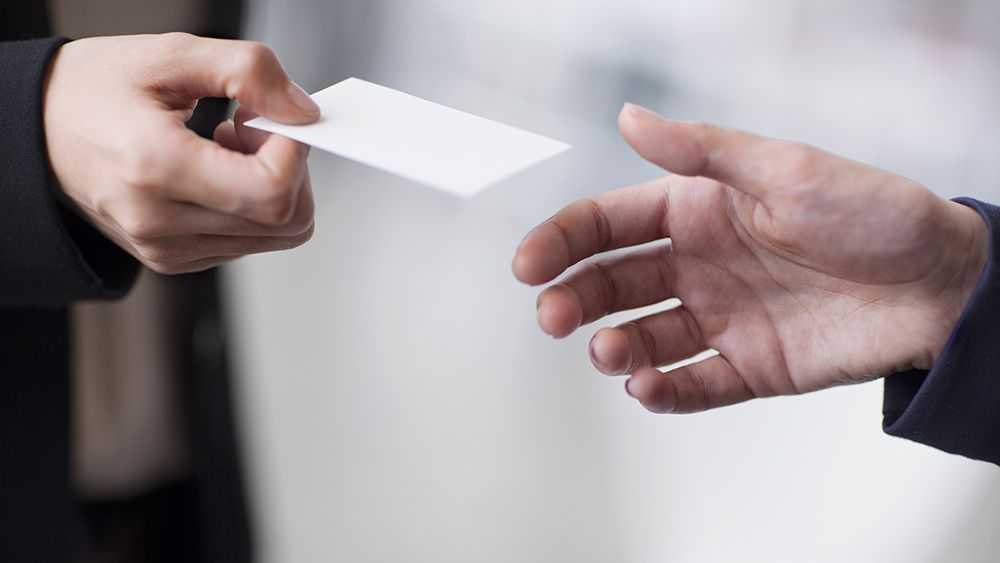 A man passes his business card to another man