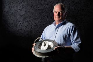 Jim Harris, Lockheed Martin Space Systems mechanical engineer, holding the OSIRIS-REx Touch-And-Go Sample Acquisition Mechanism (TAGSAM).