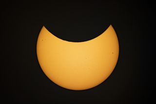 moon appears to take a bite out of the sun, blocking the top half of the sun.