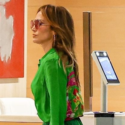 Jennifer Lopez wearing a green floral blouse with a matching maxi skirt, platform heels, and a pink custom Valentino purse in Los Angeles September 2024