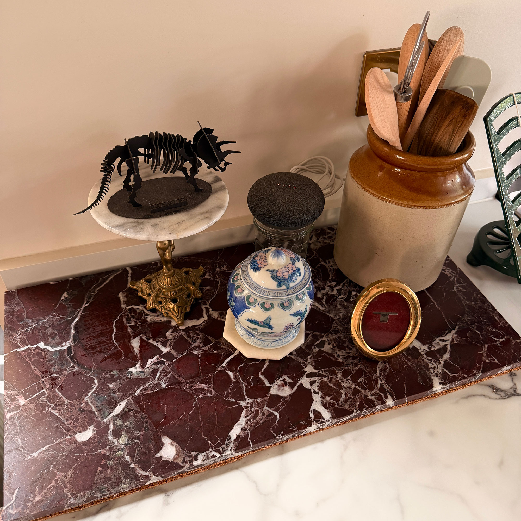 Red marble tray with mixture of ornaments and jug holding wooden utensils