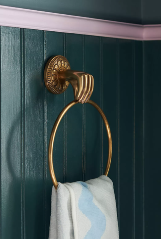 gold towel ring featuring a hand elegantly holding the ring