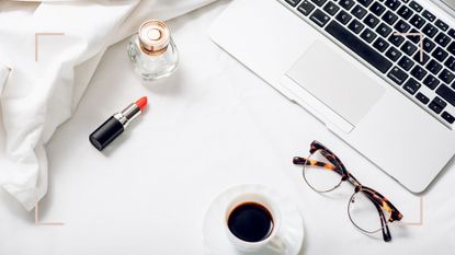 A flatlay of a laptop and perfume bottle to depict how to buy fragrance online