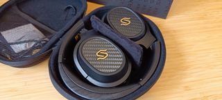 A pair of black Edifier Stax Spirit S3 headphones on a wooden desk