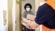 Courier guy delivers parcel to a woman at home during quarantine.