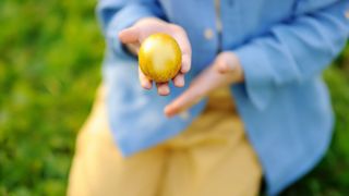 close up image of a child holding a golden easter egg