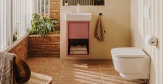 Beige bathroom with pink sink vanity unit and white sanitary ware