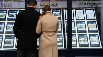 Couple looking in an estate agent&amp;#039;s window