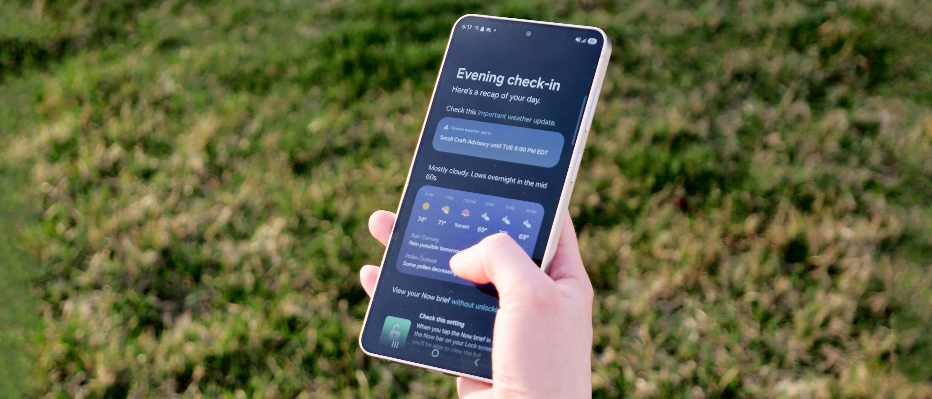 The Samsung Galaxy S26 Plus against a grass background, showcasing the Evening check-in function.