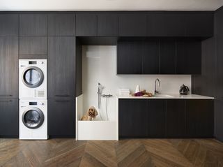 Modern utility room with dog shower by Design sSpace London cabinets are in black wood laminate with practical Carrara marble-effect composite stone on the worksurface