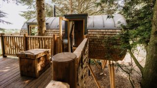 A modern, circular shaped treehouse on stilts