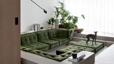sunken living room with polished concrete floors, indoor plants, sheer curtains, green upholstered cushion seats, an italian greyhound, and a large round pendant light