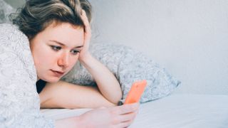 woman using her phone in bed