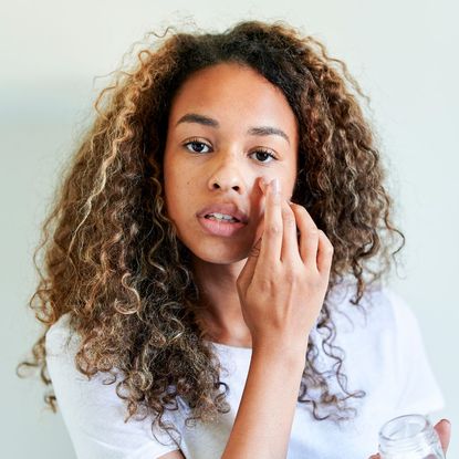 Girl applying product to cover up spot