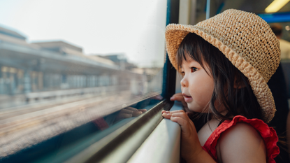 Little girl looking out of the window on a train