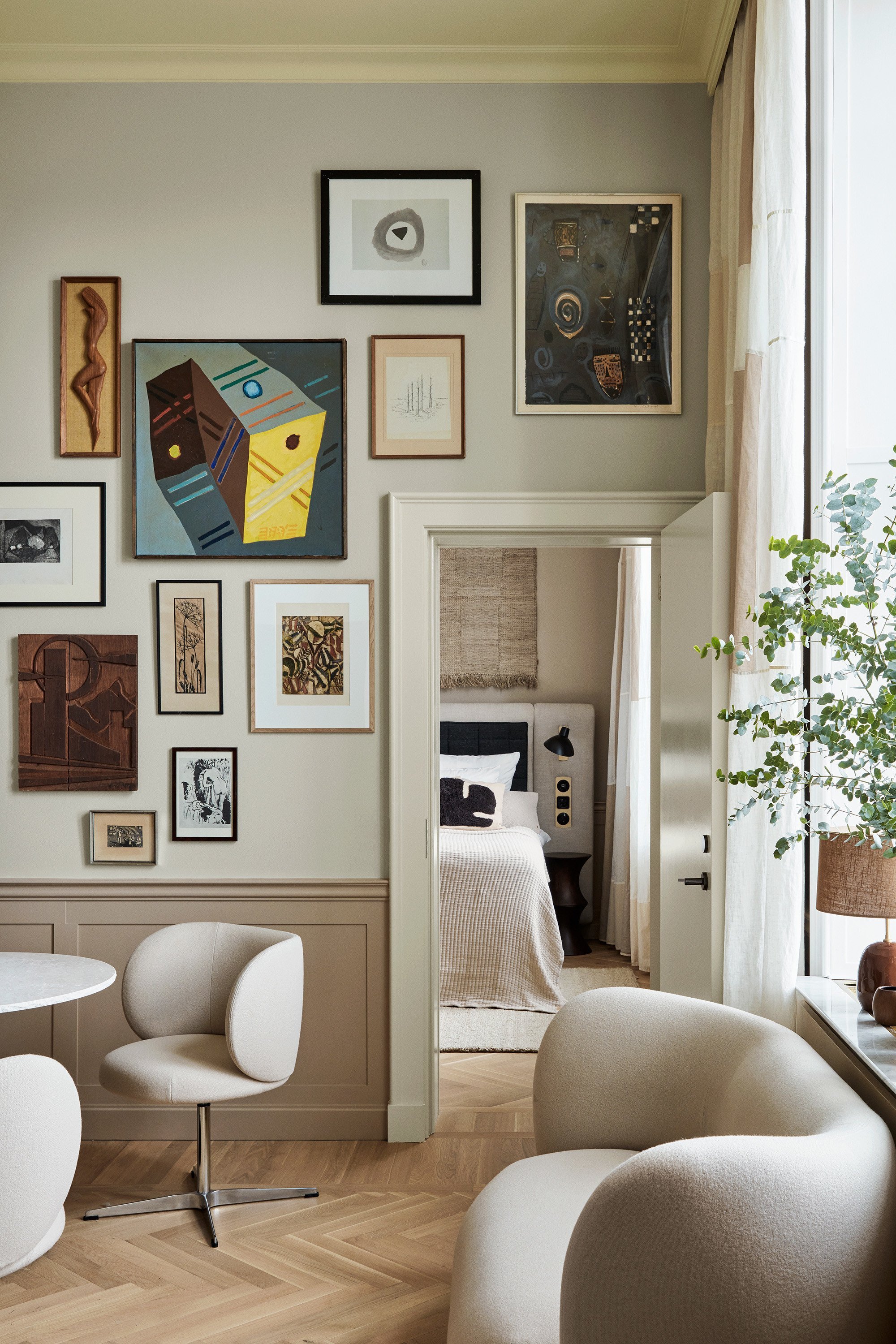 An imaginatively decorated hotel suites juxtaposes cream-tinted sculptural seats in shearling with colorful framed artworks, plants, and wooden floors.