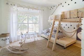 neutral children's bedroom with wooden beds, ladder, coir rug, bunting, black, white and gray bedding, mini table and chairs