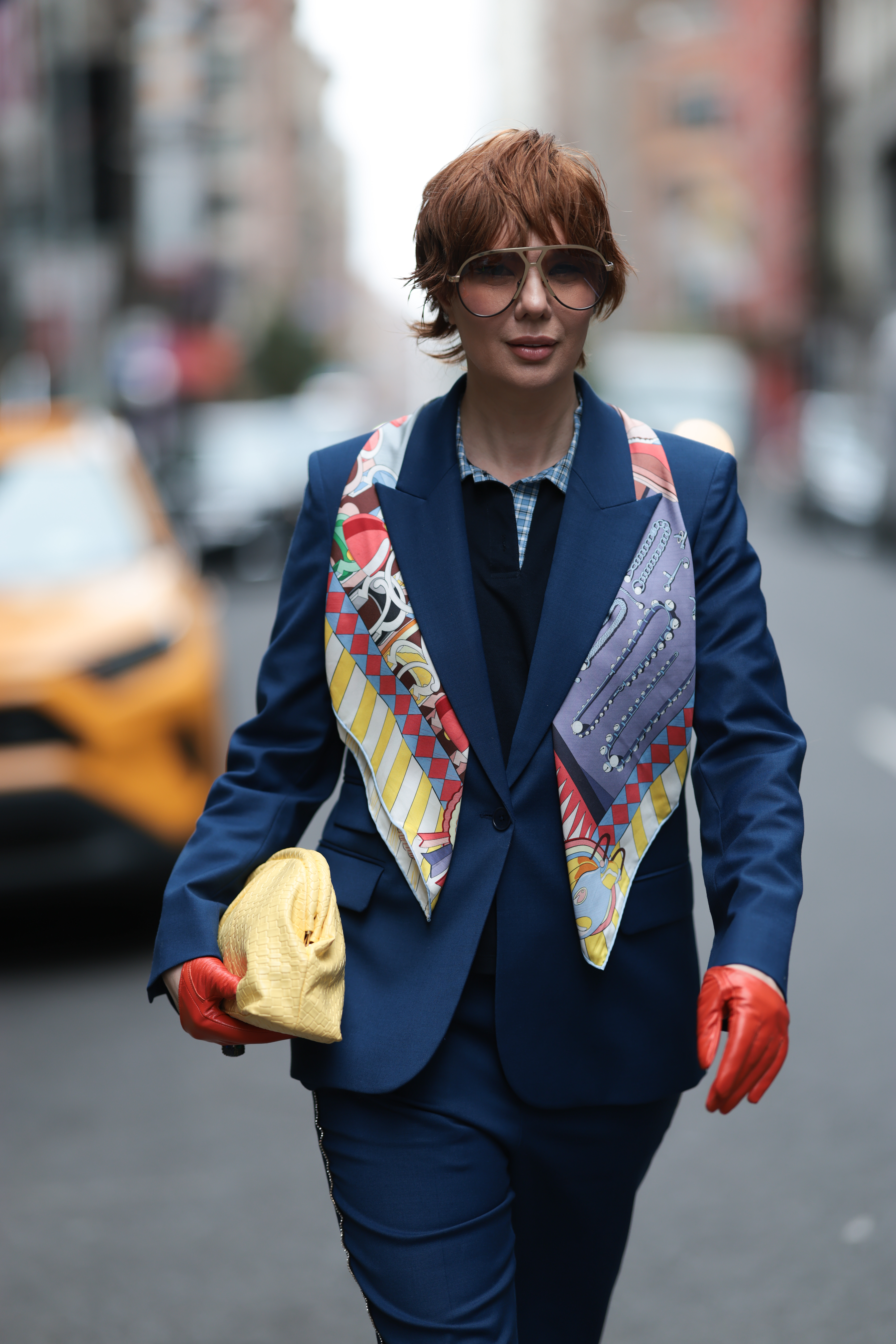 a woman with a short red pixie cut wearing a blue jacket and colorful scarf during new york fashion week