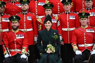 Kate Middleton wearing a green coat sitting with red uniformed soldiers on St Patrick's Day 2025