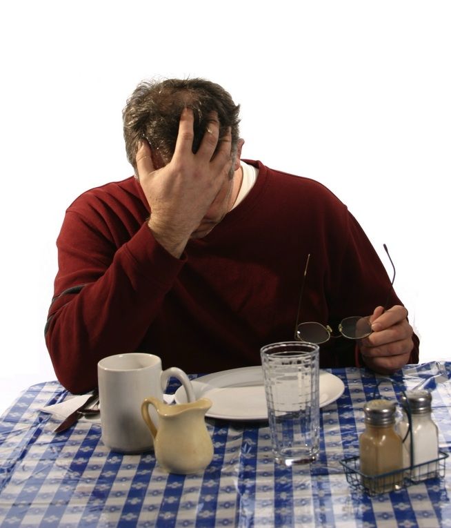 A man, upset, at a table with empty dishes.