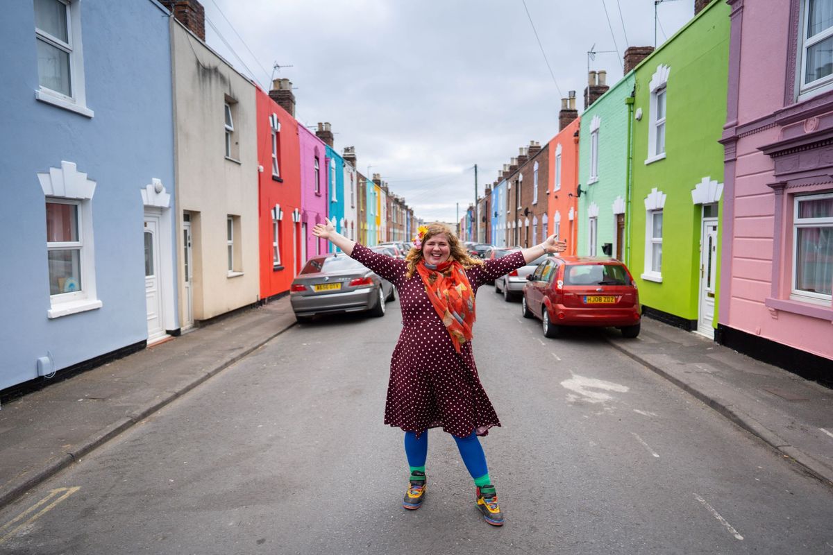 Tash stood in the middle of the street surrounded by brightly coloured houses