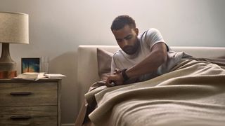 A man looking at his watch while in bed