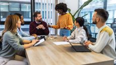 Mixture of male and female business leaders discussing AI skills and strategy in an open plan office space.