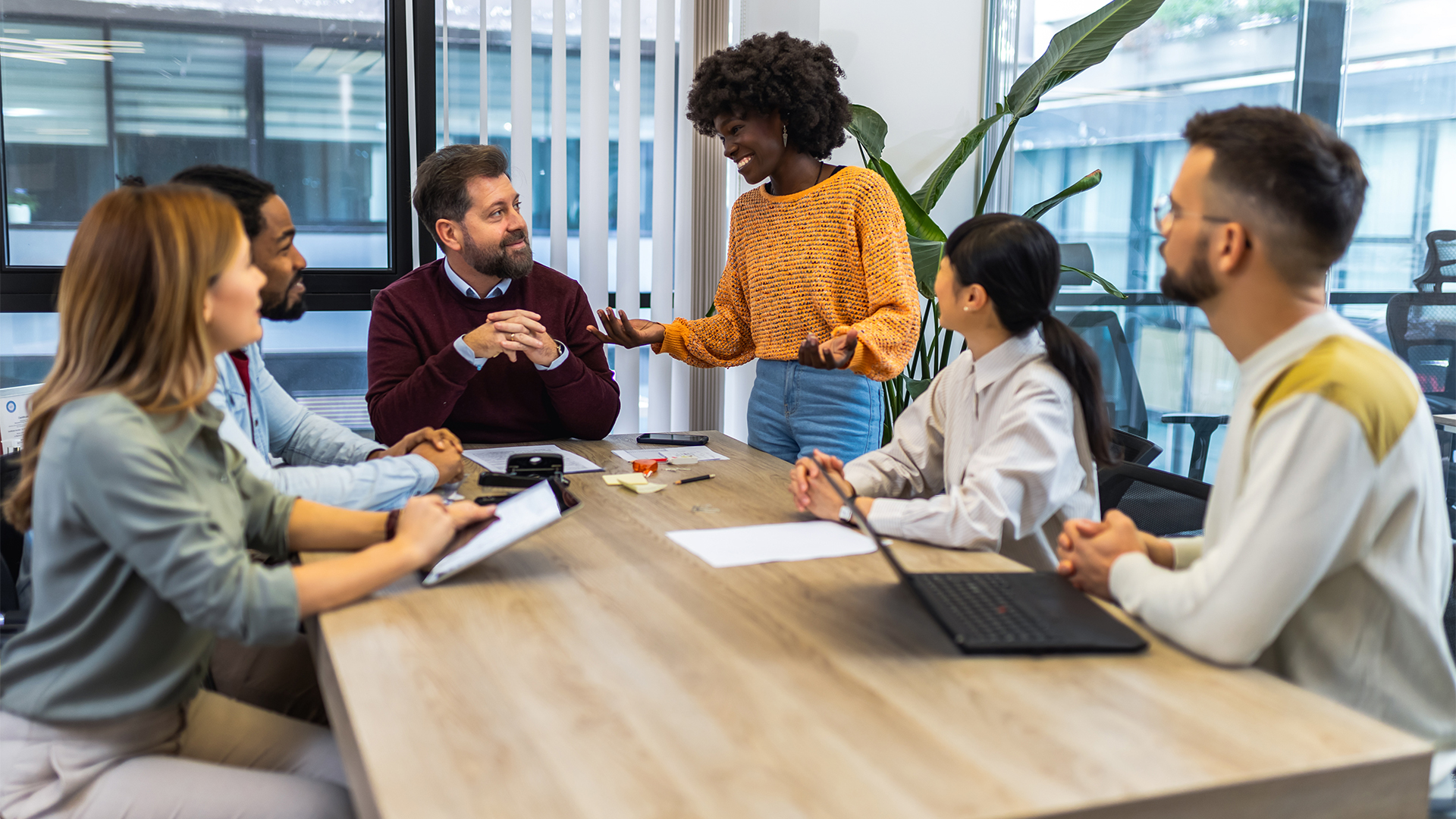 Mixture of male and female business leaders discussing AI skills and strategy in an open plan office space.