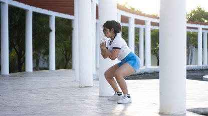 Woman holding a squat position outdoors