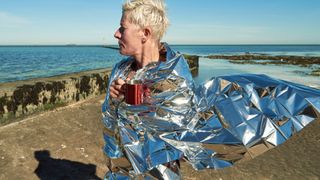 A woman on the beach wearing an emergency blanket