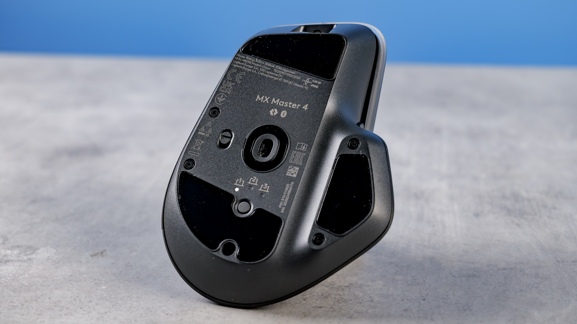 A photo of the Logitech MX Master 4 on a stone surface with a blue background