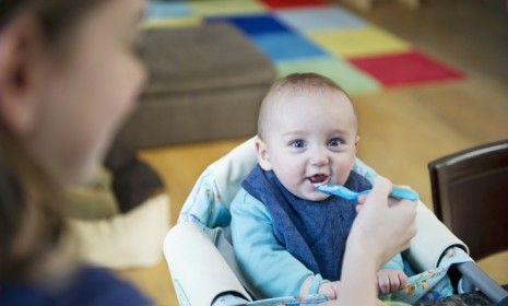 A girl feeds her baby brother